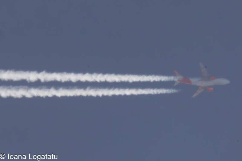 Airplane soaring high with vapor trails above